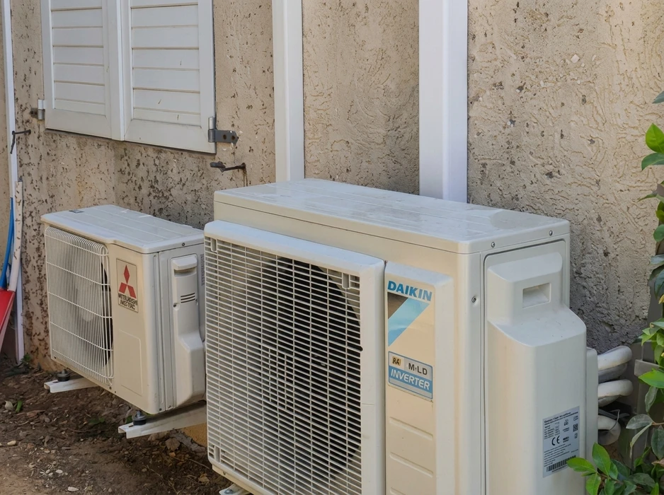 Extérieur d'un bâtiment avec deux unités extérieures de climatisation installées côte à côte contre un mur en crépi